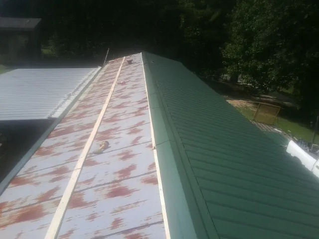 Old rusted panels beside newly installed green metal roofing — Wind Damage Roof Repair by Roofing Brothers in Paducah