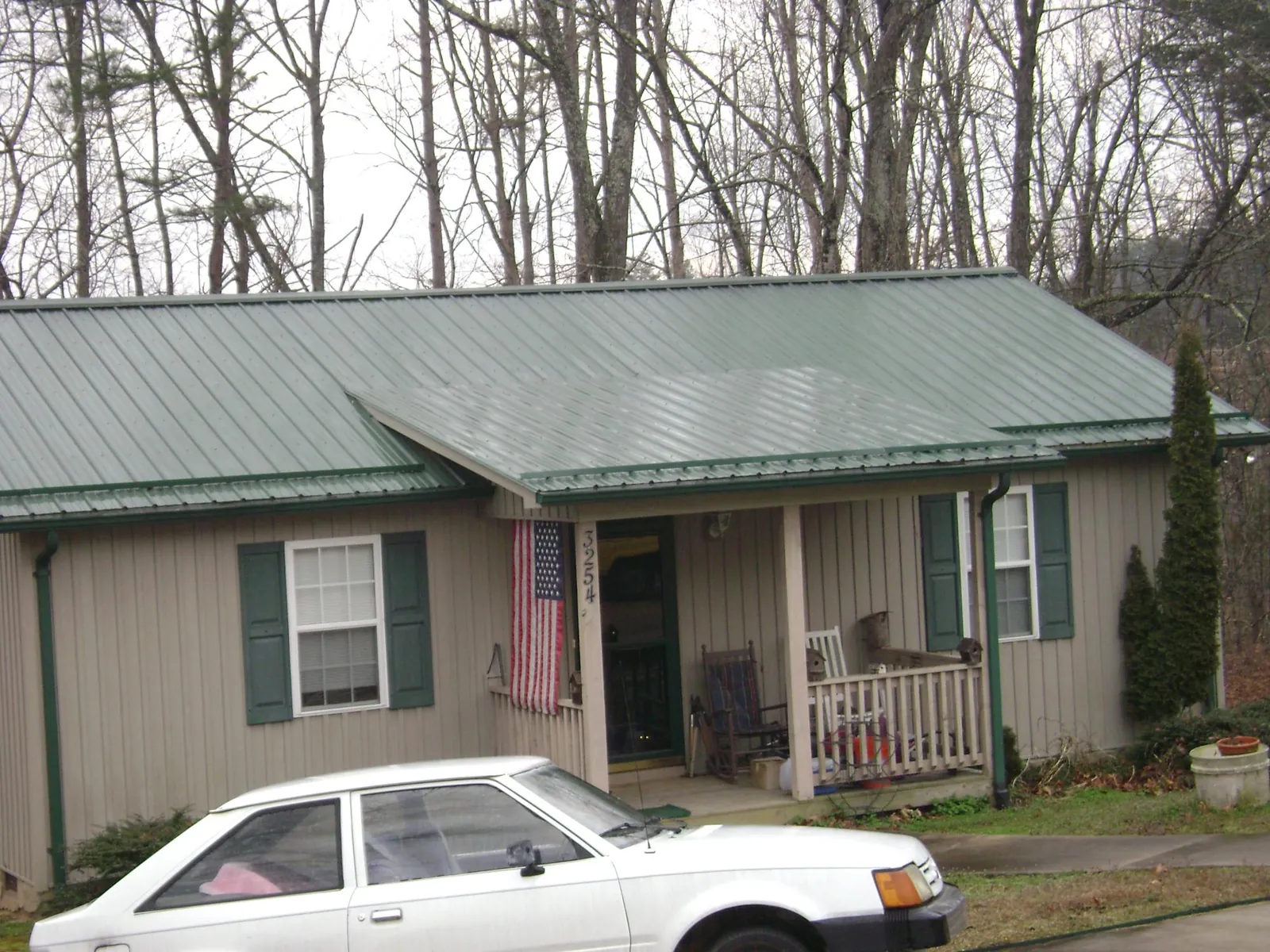 Green metal roof and front porch on a tan sided cottage in Paducah