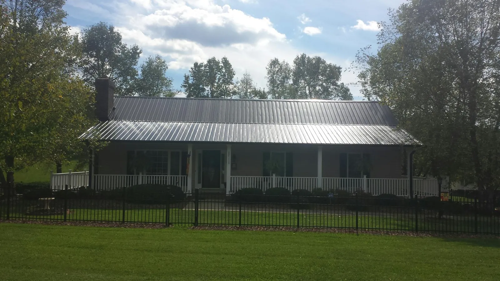 Gray metal roof on a brick ranch with a full width front porch — Gutter Guard Installation work by our crew in Paducah