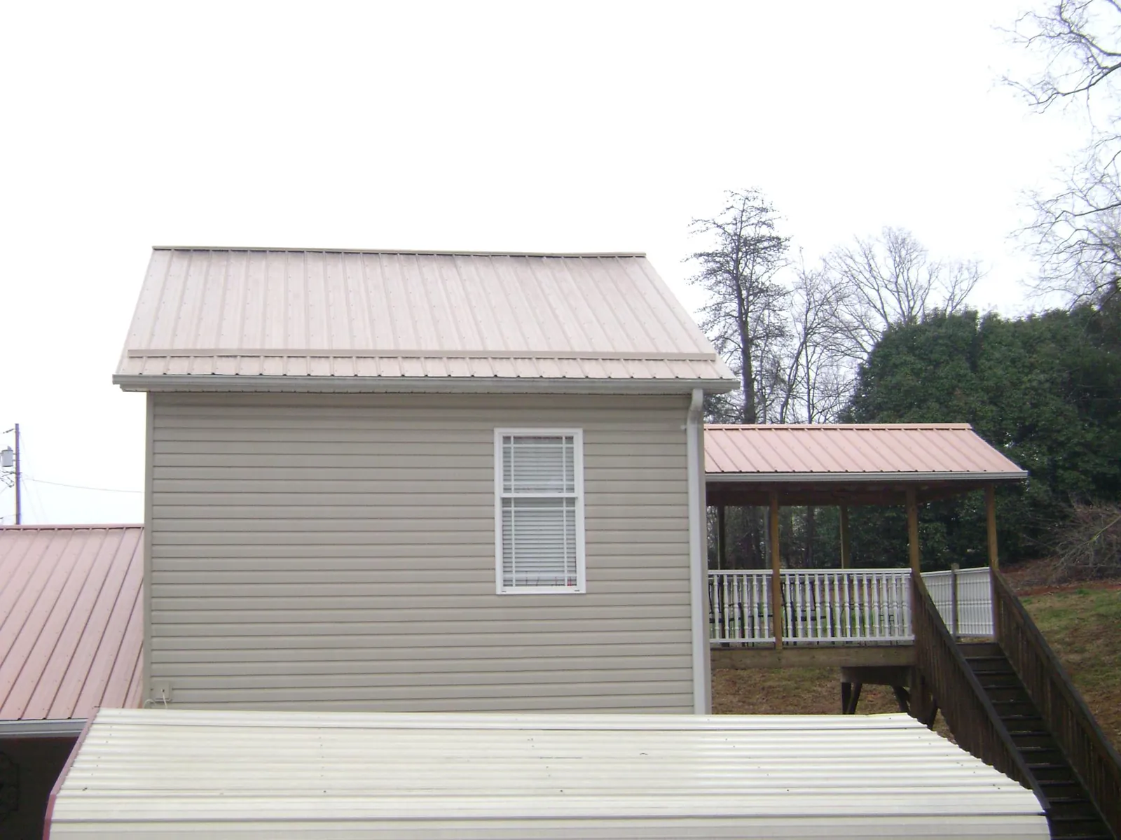 Tan metal roofs on a two story addition and attached porch, from a Roof Replacement job in Paducah