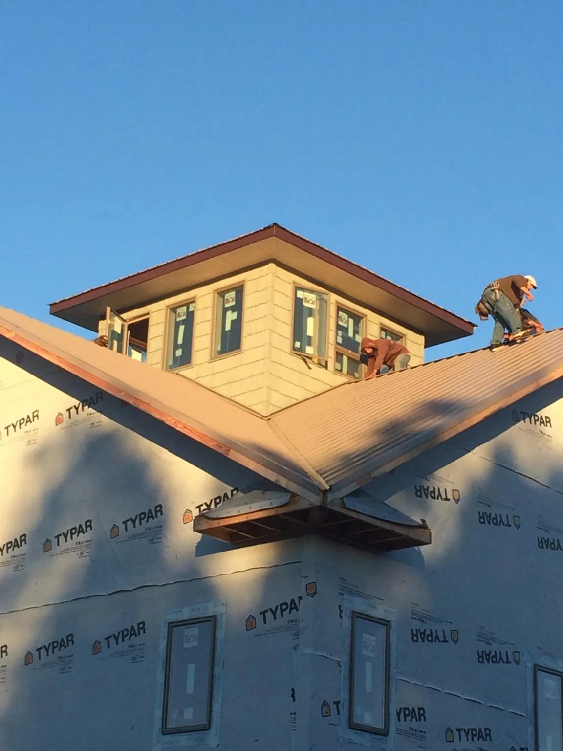 Roofers working around a rooftop cupola on a new metal roof at sunset — Roof Waterproofing in Paducah by Roofing Brothers